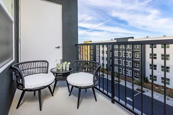 a balcony with two chairs and a table  Solasta apartment building in background at Solasta, Sacramento, CA, 95831